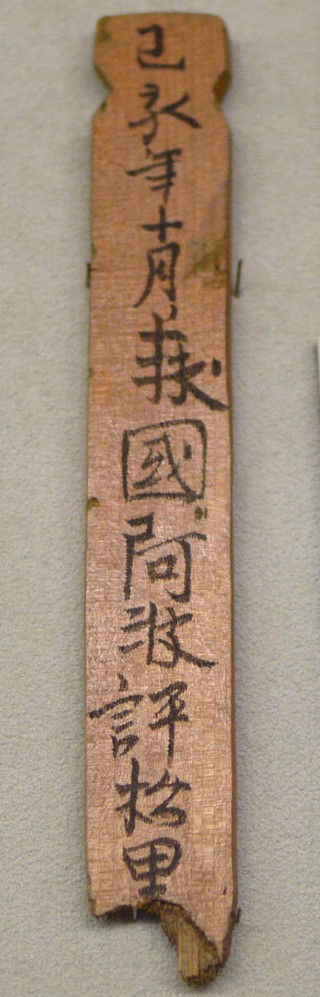 藤原宮跡から出土した木簡の複製。縦長の木の札に「阿波評松里」などの文字が墨で書かれている